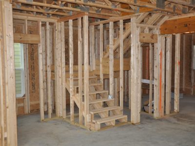 Une ossature de cloison avec un escalier en bois non terminé.